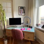 Person richtet ergonomischen Home‑Office‑Arbeitsplatz mit Monitor und Tastatur ein