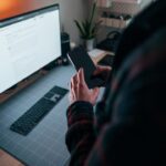 Ein Monitorarm hält einen ultrawiden Bildschirm schwebend über einem Schreibtisch, schafft freie Arbeitsfläche und ermöglicht eine ergonomische Anpassung.