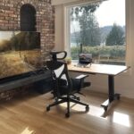 Ein moderner höhenverstellbarer Schreibtisch in einem hellen Home Office, der sich gerade in der Bewegung zwischen Steh- und Sitzhöhe befindet.