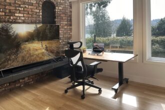 Ein moderner höhenverstellbarer Schreibtisch in einem hellen Home Office, der sich gerade in der Bewegung zwischen Steh- und Sitzhöhe befindet.