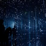 Ein silberner Monitorarm hält einen großen Bildschirm über einem schlichten Schreibtisch mit Tastatur, bereit für ein ergonomisches Home-Office.