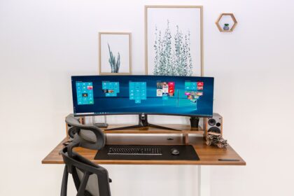 Ein schlanker Monitorarm hält einen ultrawiden Bildschirm stabil über einem aufgeräumten Schreibtisch im Home-Office.