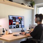Ein moderner, ergonomischer schwarzer Büro-Kopfhörer (Jabra Evolve2 85) liegt auf einem aufgeräumten Schreibtisch im Home-Office, neben einem Laptop und einer Kaffeetasse.