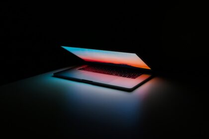 Ein kompakter, schwarzer DYMO-Beschriftungsgerät mit QWERTZ-Tastatur liegt auf einem aufgeräumten Schreibtisch, neben beschrifteten Ordnern und Boxen.